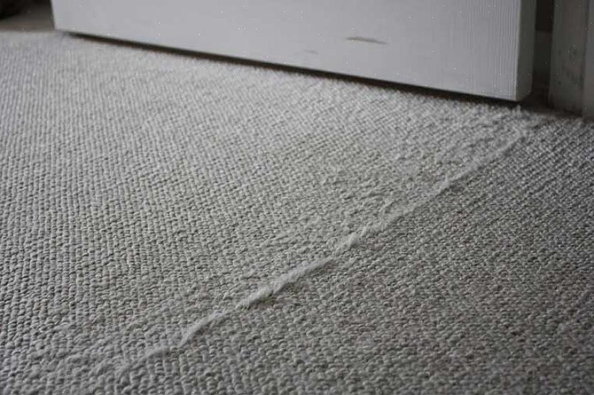 Centrare una linea di nastro adesivo per tappeti sotto i due bordi tagliati dei due pezzi di moquette